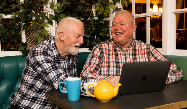 two men laughing at a computer screen